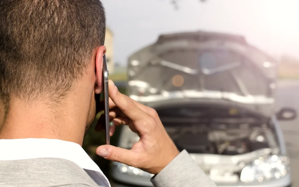 Driver making a phone call beside his car after a motor vehicle accident